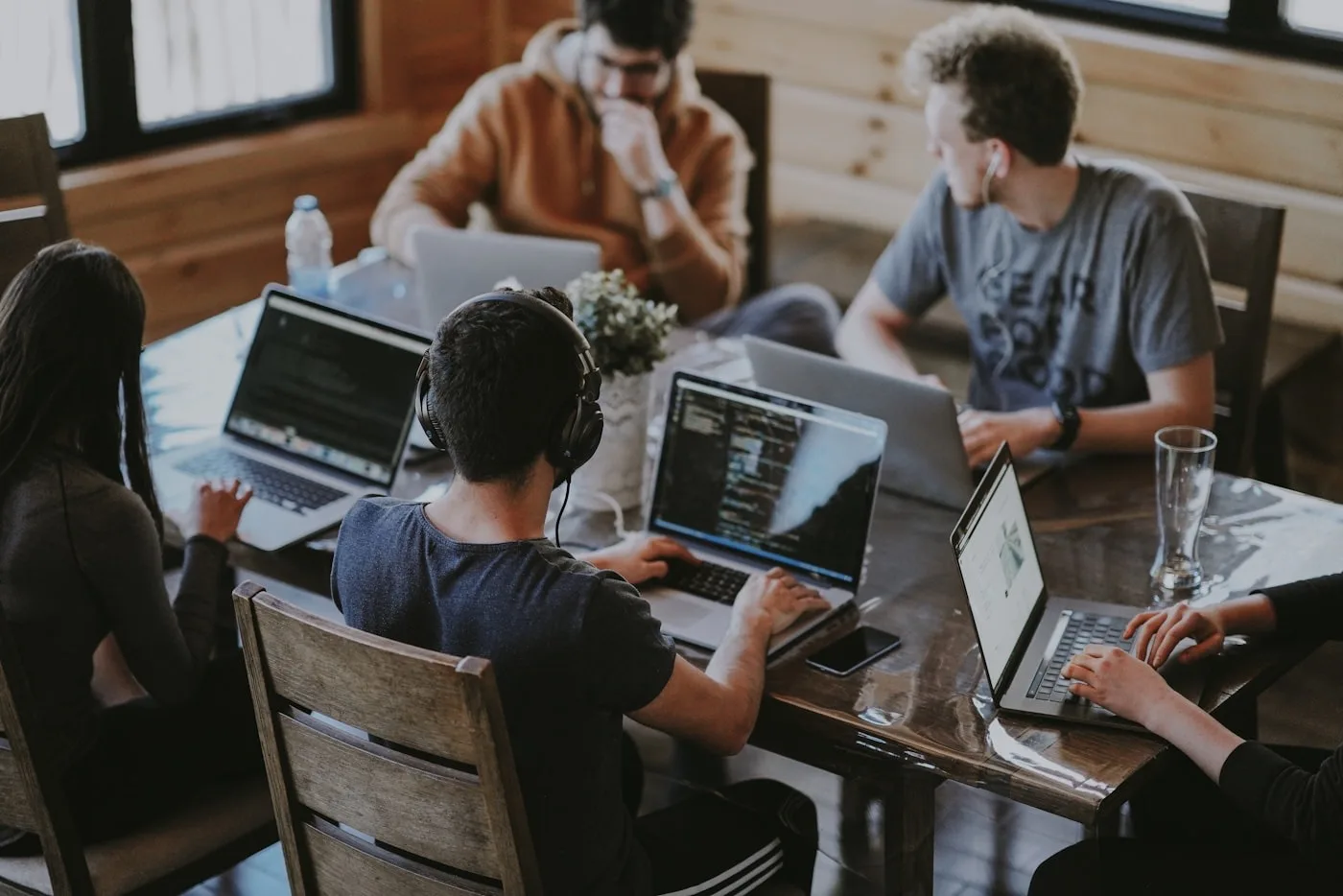Growing development team coding side by side around a shared project table