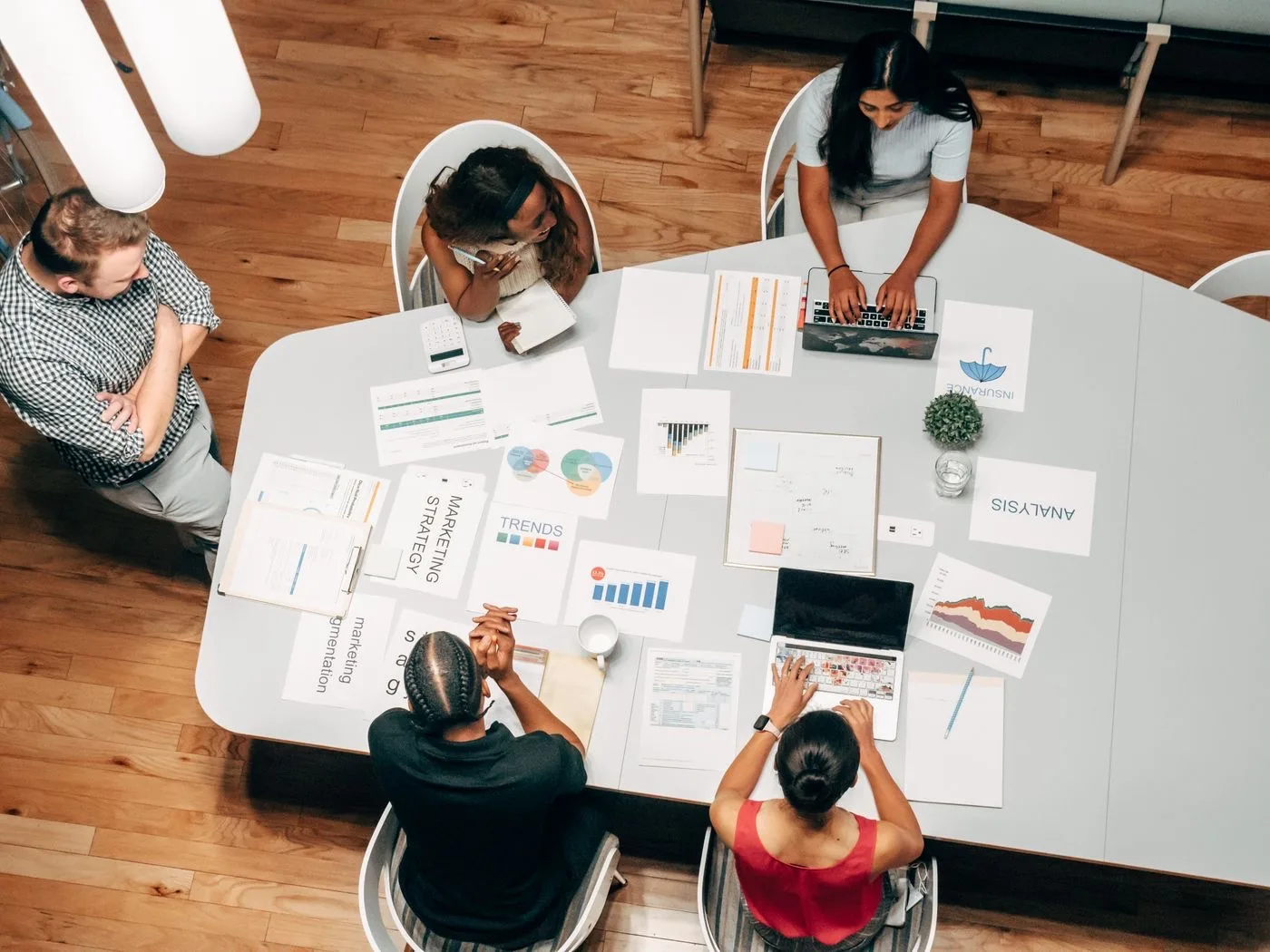 Marketing team reviewing strategy documents, charts, and campaign plans around a table