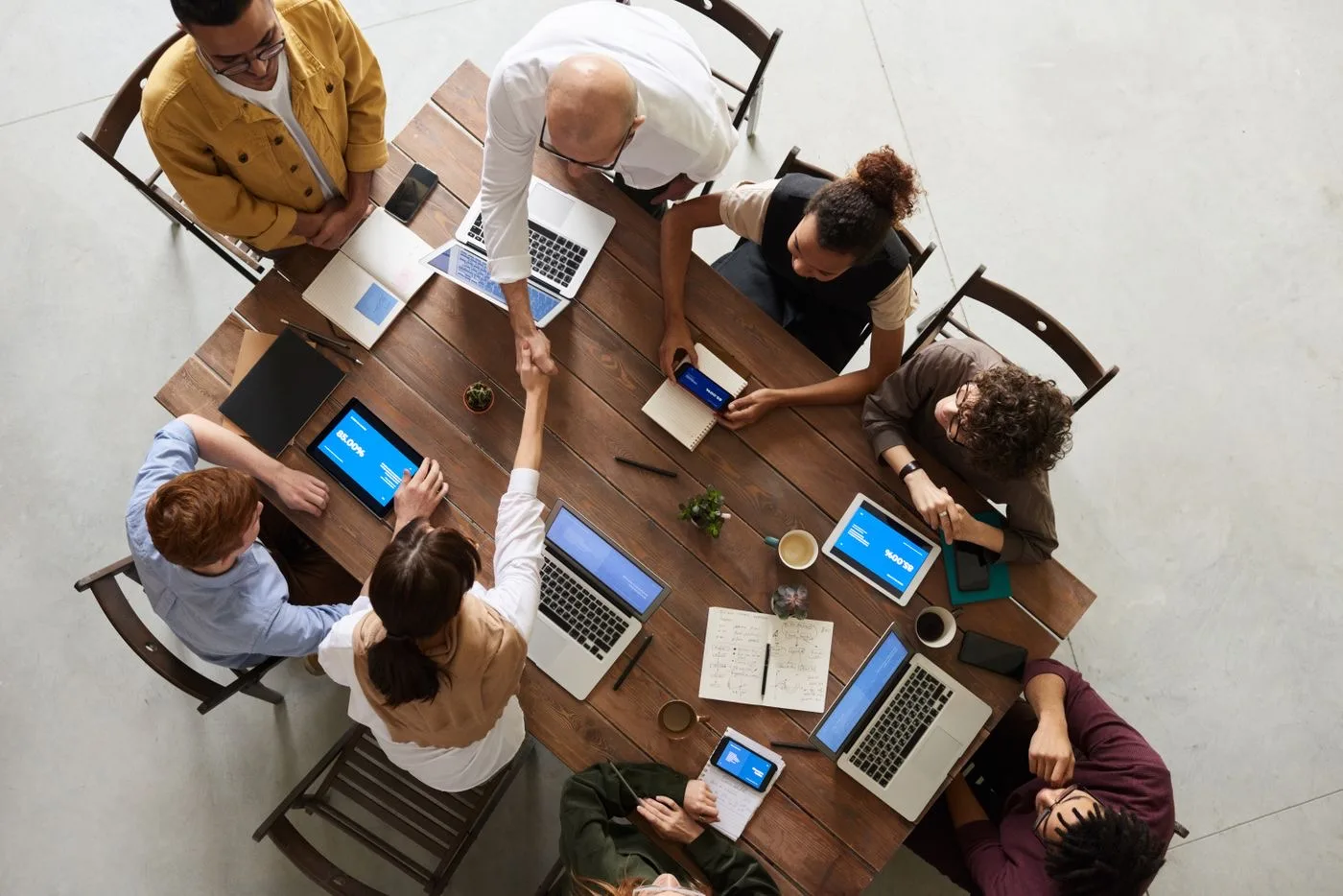 Diverse cross-functional delivery team collaborating around laptops and tablets