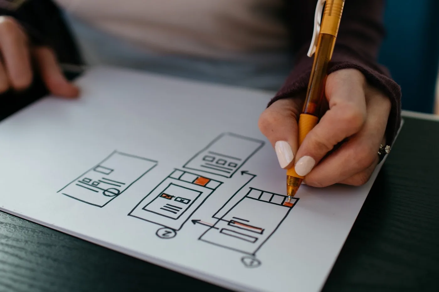 Designer sketching mobile product wireframes and screen flows by hand