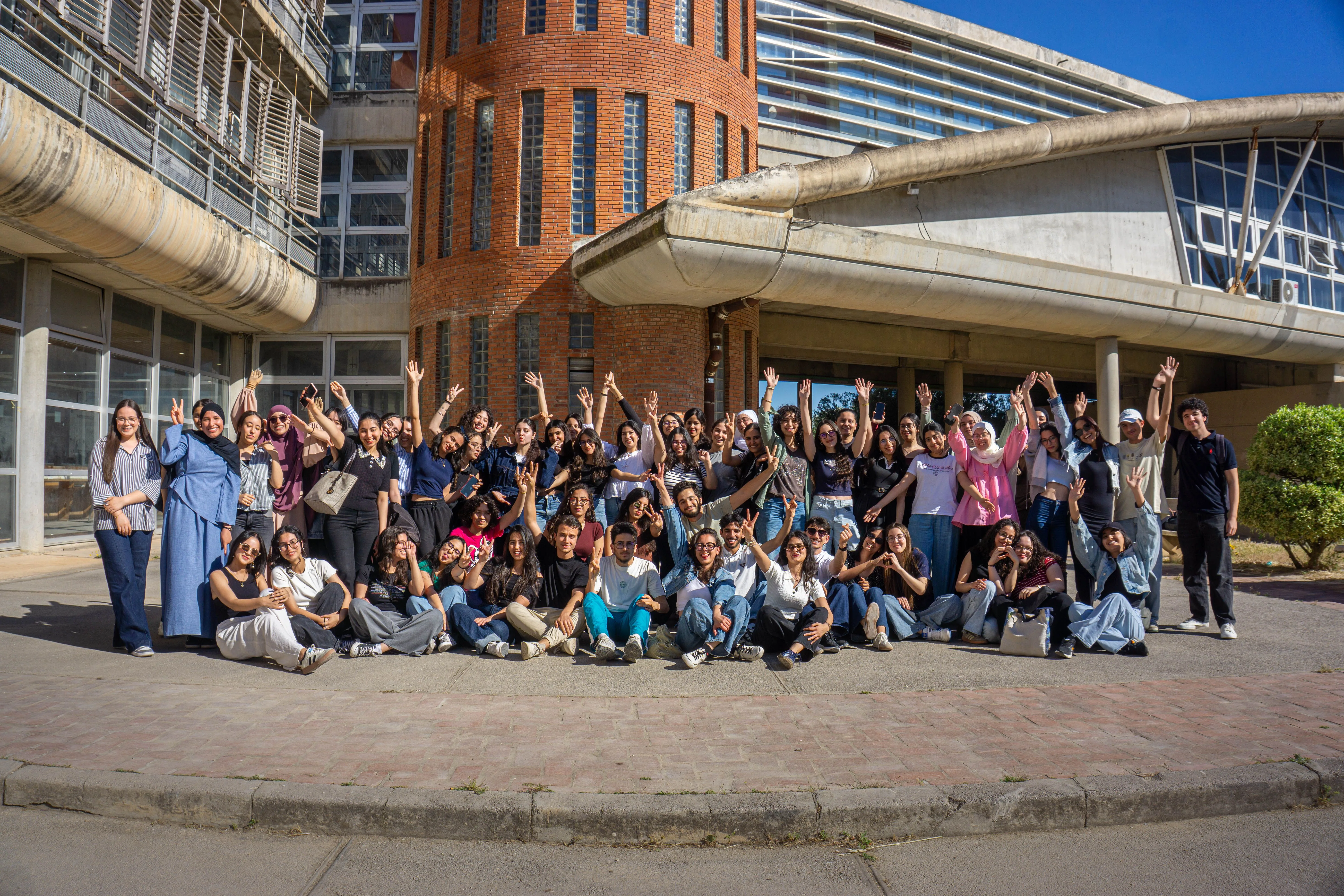 Large diverse team posing in rows outdoors in front of a modern building