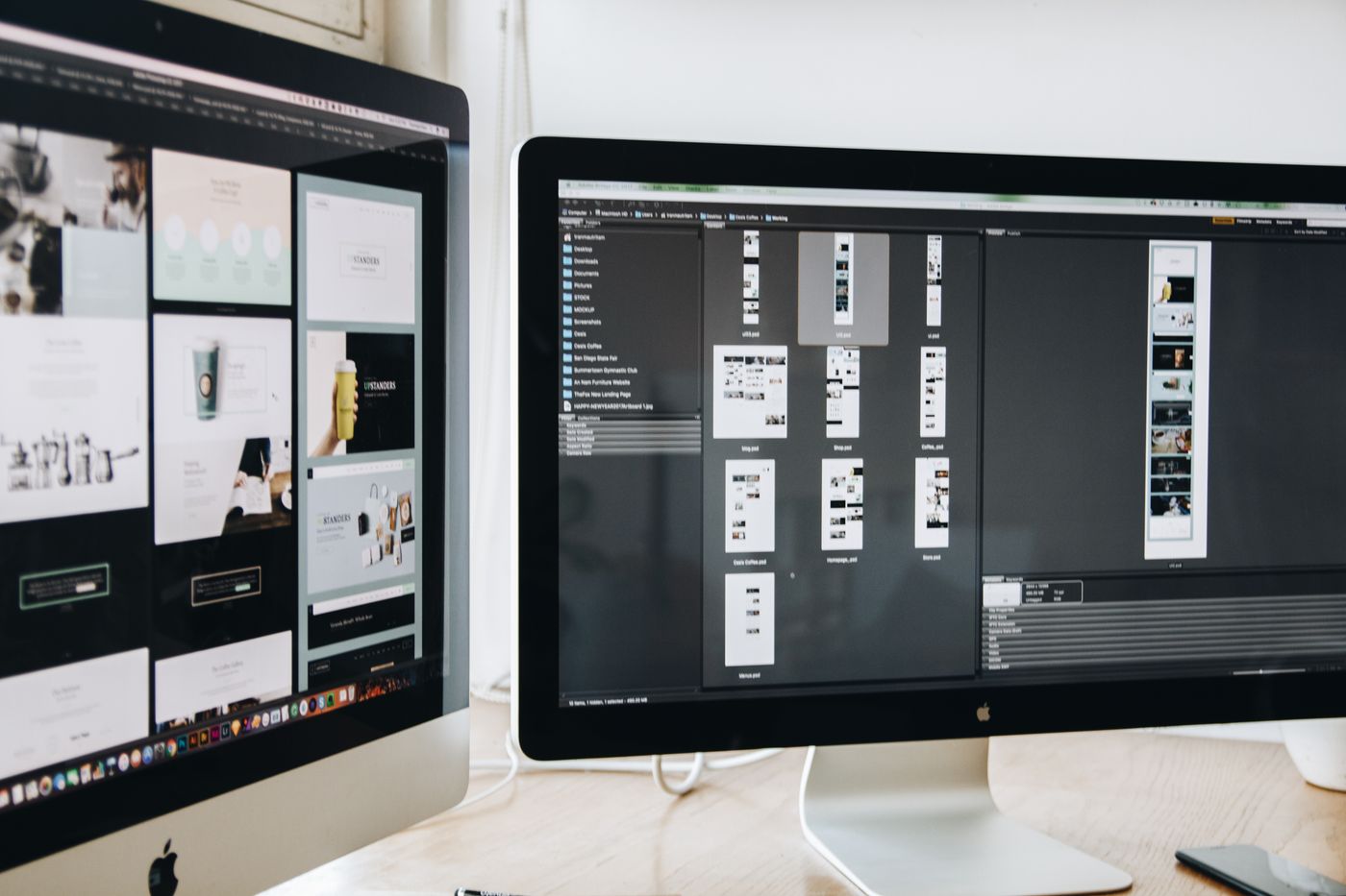 Design studio with dual monitors showing UI layouts