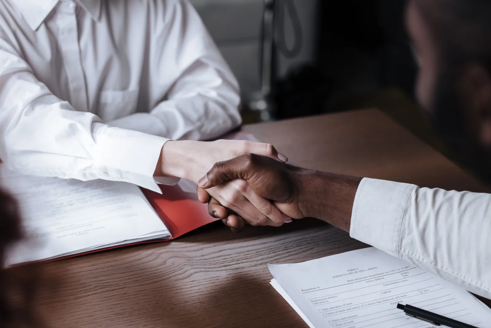 Business professionals shaking hands over project documents