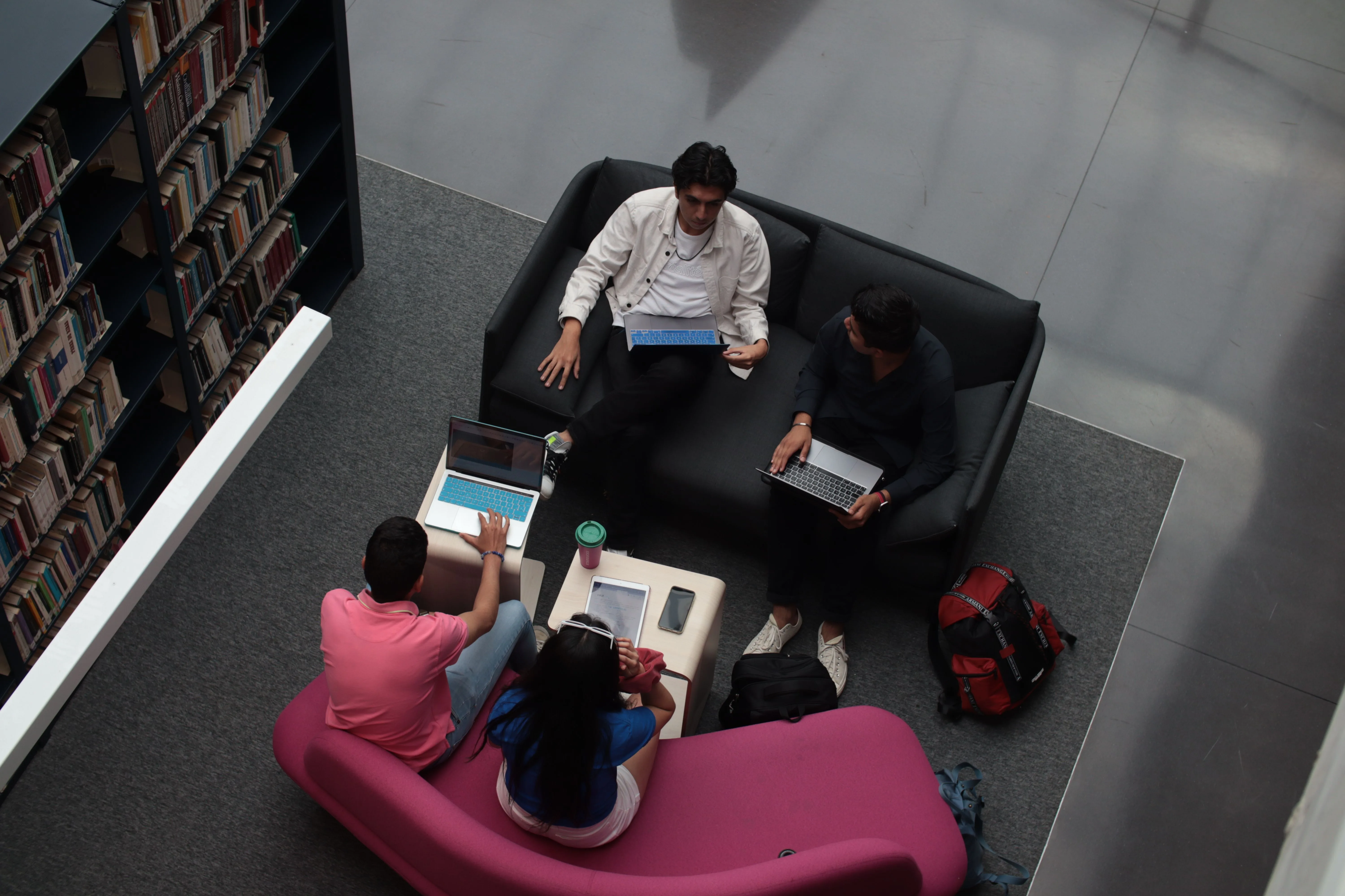Team collaborating with laptops in a bright resource library lounge
