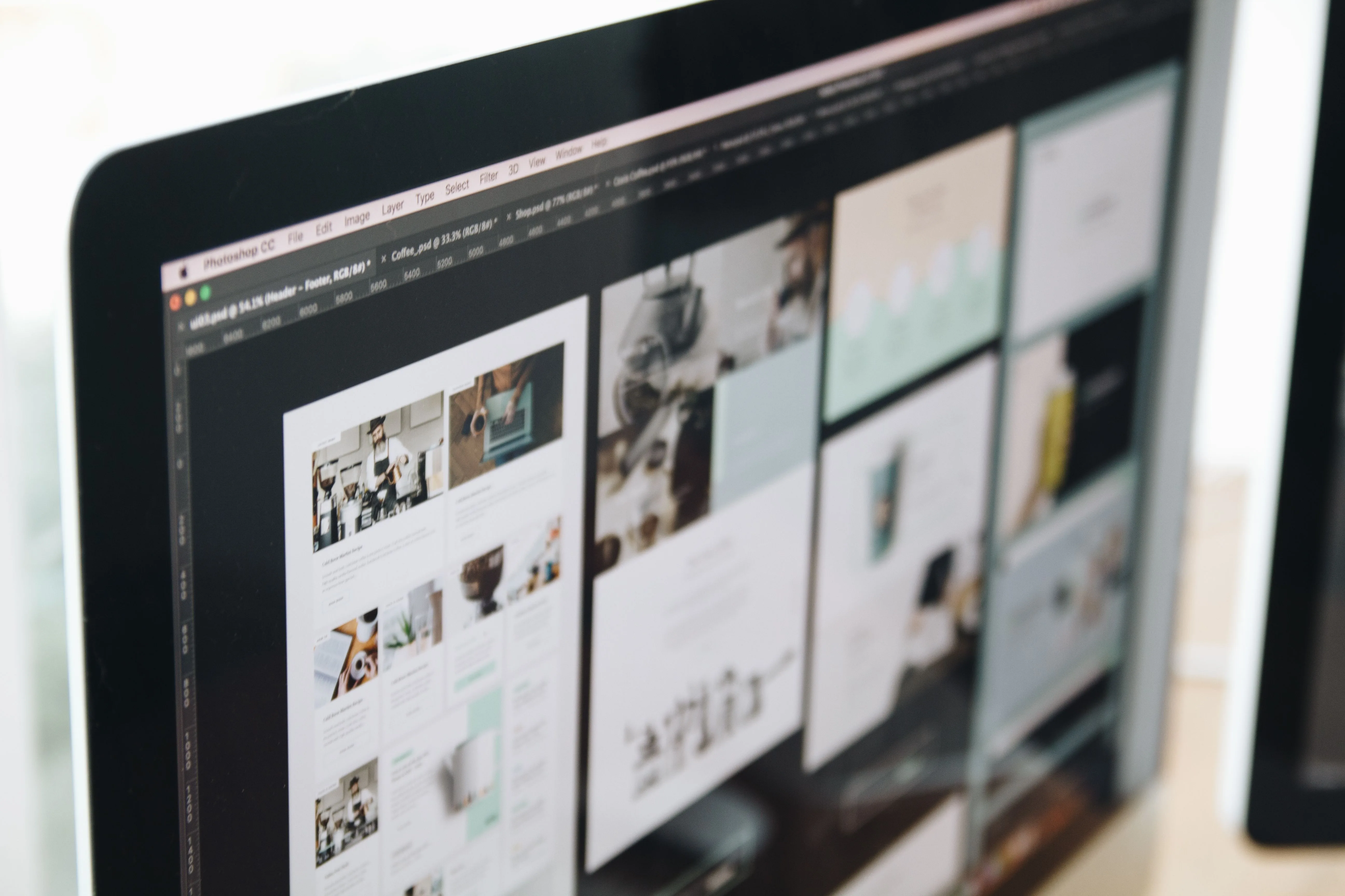 Designer reviewing a website layout on a large monitor in a modern workspace